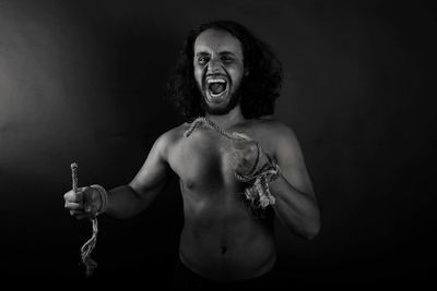 Portrait of furious man screaming against black background