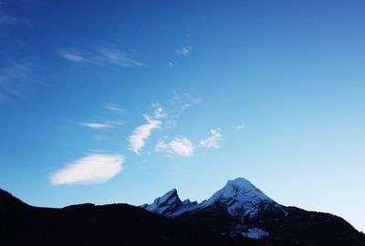 Low angle view of snowcapped mountain against blue sky