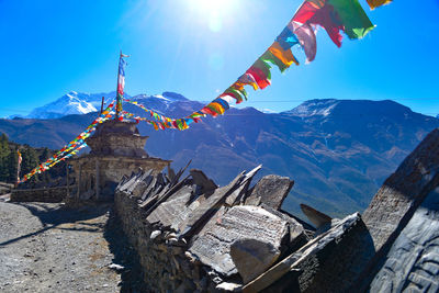 Colorful prayer flags hanging against mountains during sunny day