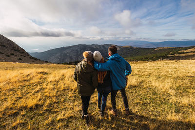 Rear view of couple on mountain against sky