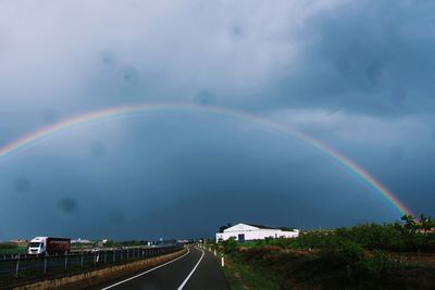 Rainbow over road in city against sky