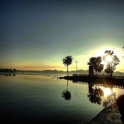 Reflection of trees in water at sunset