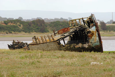 Abandoned boat on field against sky