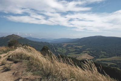 Mountain landscape view from hill visible one man hiking in background