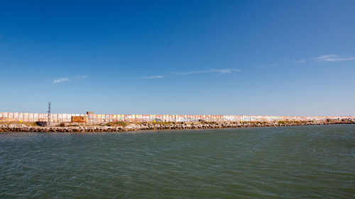 Sea by buildings against blue sky