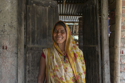 Portrait of smiling woman standing against wall