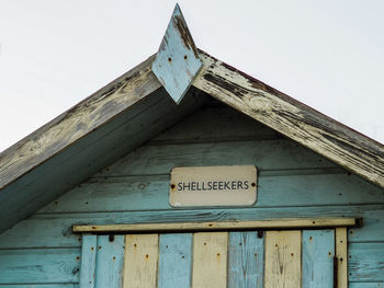 Low angle view of sign on wall against sky