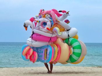 Full length of multi colored umbrellas on beach against sky