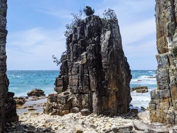 Rock formation on beach against sky