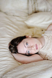 Portrait of young woman lying on bed