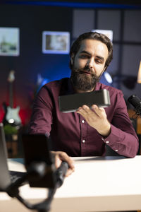 Portrait of man using mobile phone while sitting on table