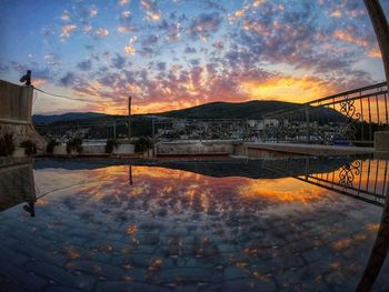 Bridge over buildings against sky during sunset