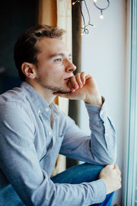 Close-up of man looking out window