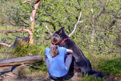 Rear view of woman sitting on rock in forest