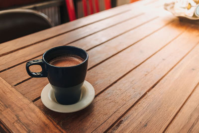 Blue mug of hot chocolate on wooden table in a cafe.