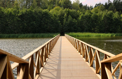 Footbridge over lake against trees
