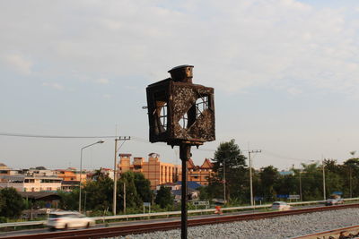 Close-up of metallic structure by railroad tracks against sky