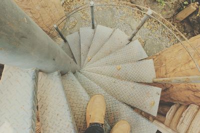 Low section of man standing on spiral staircase