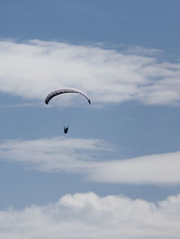 Low angle view of person paragliding against sky