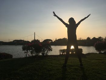 Silhouette person standing by plants against sky during sunset