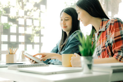 Young woman using smart phone on table