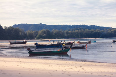 Boats moored on shore against sky