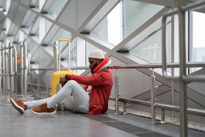 Aweary young african american male sits with smartphone after announcement of cancellation of flight