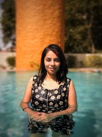 Portrait of smiling young woman standing in swimming pool