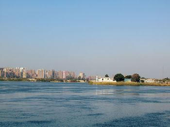 Sea by buildings against clear blue sky