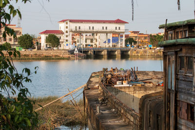Buildings by river against sky