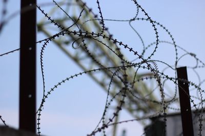 Low angle view of barbed wire against sky