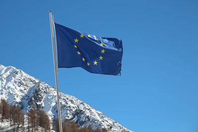 Low angle view of european union flag against snowcapped mountain