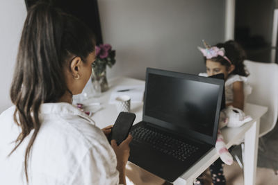 Woman working from home, girl on background