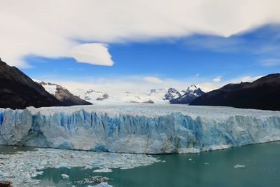 Glacier in sea against mountains and sky during winter