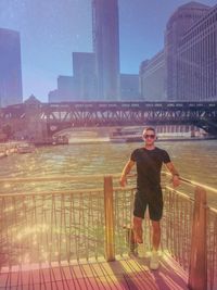 Portrait of man standing by railing in city against sky