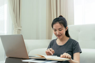 Young woman using phone while sitting on table