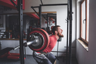 Man lifting barbell while exercising at gym