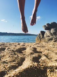 Low section of person on beach against sky