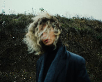 Portrait of young woman standing against plants