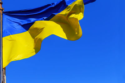 Low angle view of ukrainian flag waving against clear blue sky