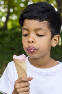 Close-up of a young boy eating ice-cream outdoors in a park.