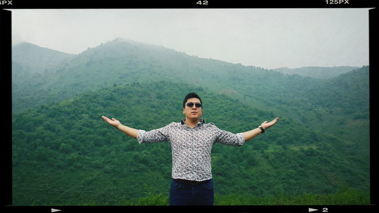 transfer print, mountain, lifestyles, leisure activity, casual clothing, young adult, auto post production filter, person, standing, mountain range, smiling, looking at camera, portrait, landscape, grass, young women, three quarter length, full length