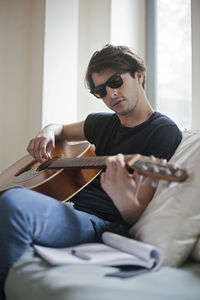 Young musician writing songs on an acoustic guitar