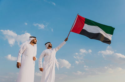 Low angle view of men standing against sky