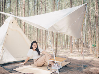 Happy asian teenage girl in front of camp tent. outdoor activity.