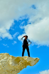 Low angle view of man standing against blue sky