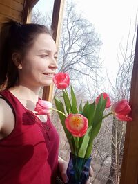 Young woman holding red flowering plants