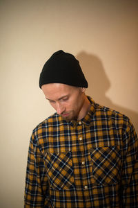 Young man looking away against wall