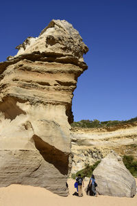 People on rock formation against clear sky