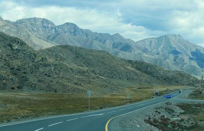 Road leading towards mountains against sky